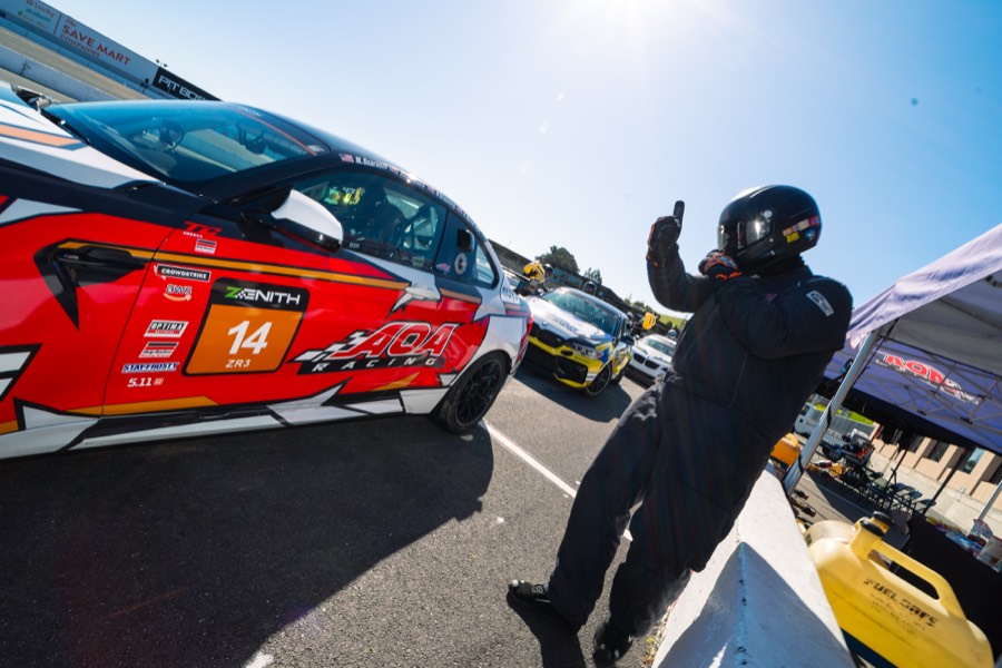 Ren giving a thumbs up beside the car